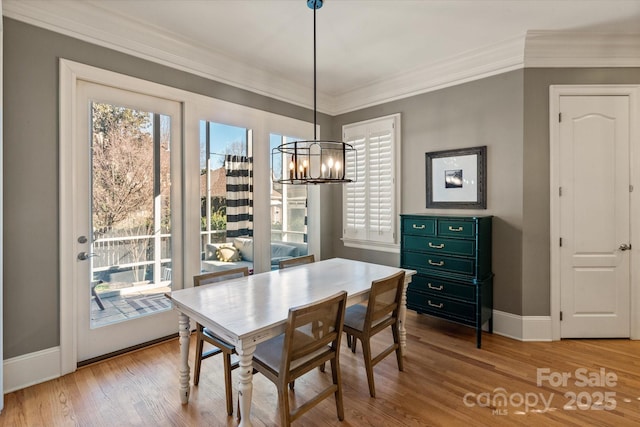 dining room with a notable chandelier, light wood-style flooring, ornamental molding, and baseboards