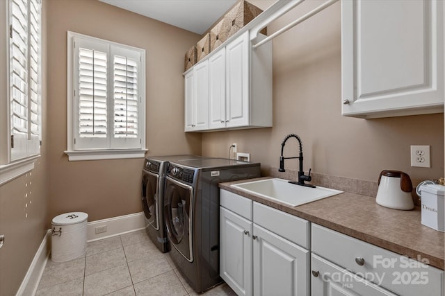 washroom with light tile patterned floors, cabinet space, washing machine and dryer, a sink, and baseboards