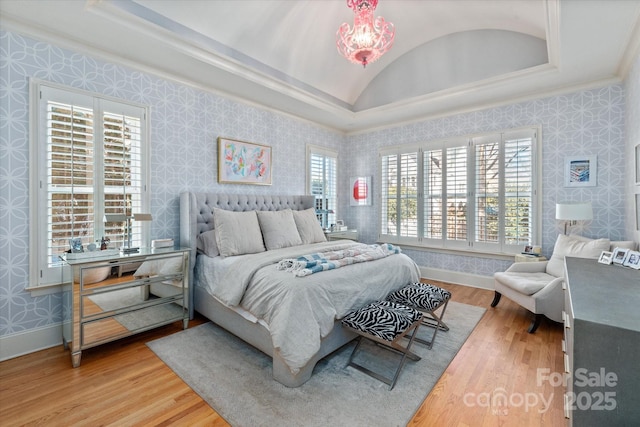 bedroom with lofted ceiling, wood finished floors, baseboards, and wallpapered walls