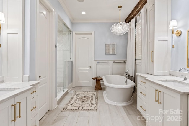 full bath with a stall shower, wainscoting, a sink, a freestanding bath, and two vanities