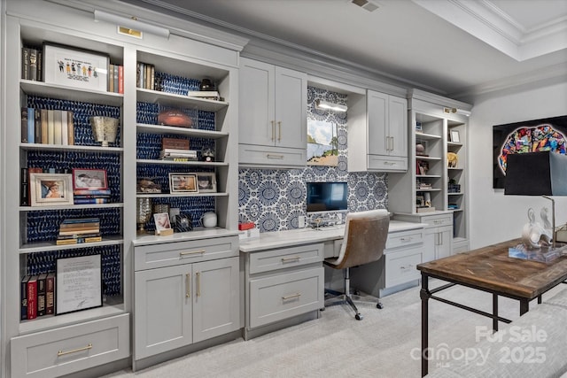 office featuring ornamental molding, built in desk, and light colored carpet