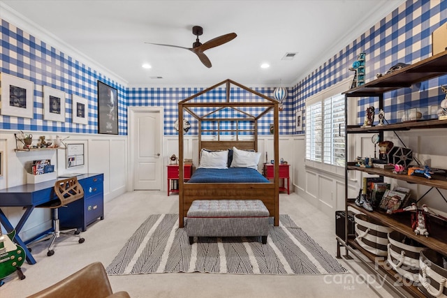 bedroom with crown molding, visible vents, light carpet, wainscoting, and wallpapered walls