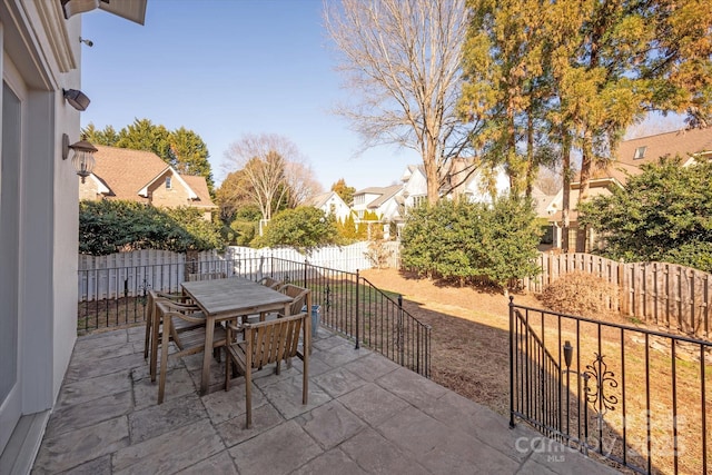 view of patio / terrace with outdoor dining space, a fenced backyard, and a residential view