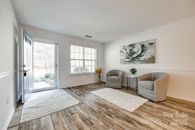 sitting room with baseboards, visible vents, and wood finished floors