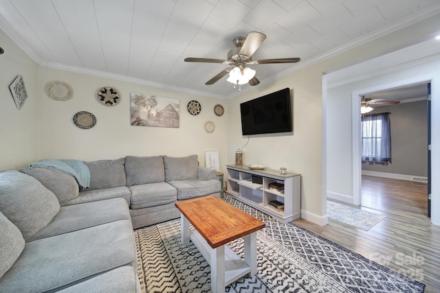 living room with a ceiling fan, baseboards, crown molding, and wood finished floors