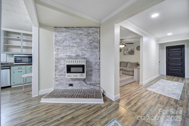 interior space with heating unit, a fireplace, ornamental molding, and wood finished floors