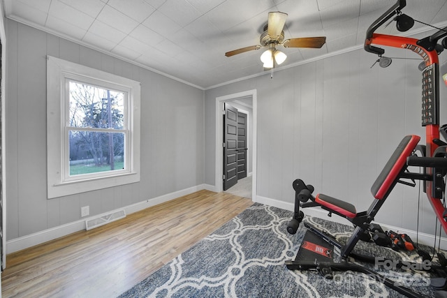 workout area featuring crown molding, visible vents, a ceiling fan, wood finished floors, and baseboards