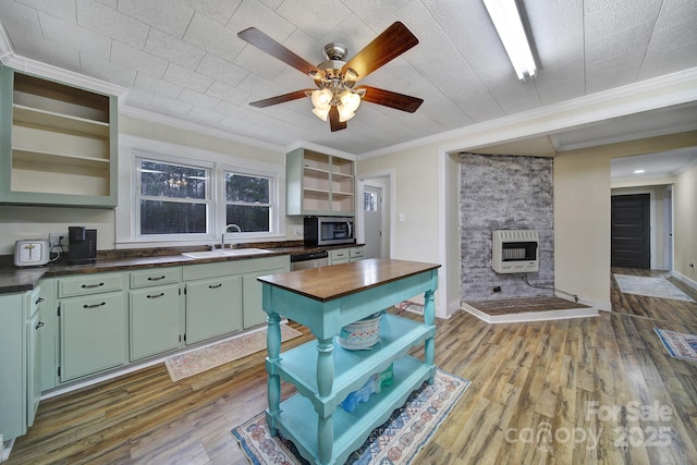 kitchen featuring wood finished floors, heating unit, stainless steel appliances, open shelves, and a sink