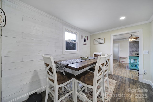 dining area with baseboards, wood finished floors, and crown molding