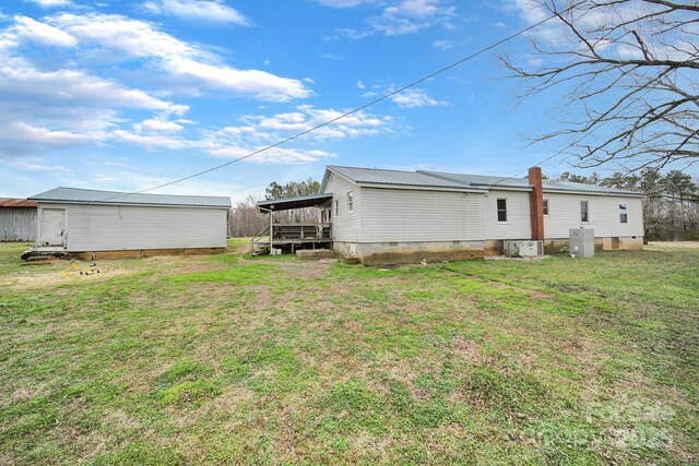 rear view of property featuring crawl space, metal roof, and a lawn