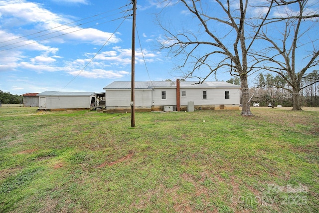 rear view of house featuring crawl space, metal roof, and a yard