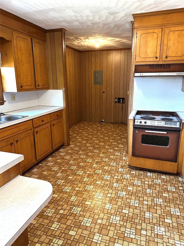 kitchen featuring brown cabinetry, light countertops, range, and under cabinet range hood