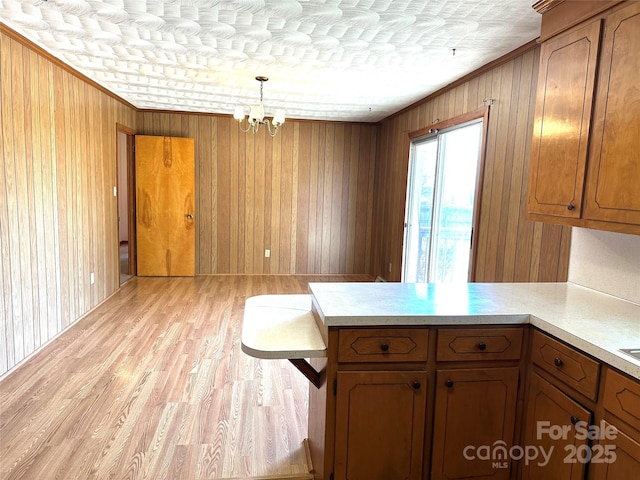 kitchen featuring light countertops, a peninsula, brown cabinets, and pendant lighting