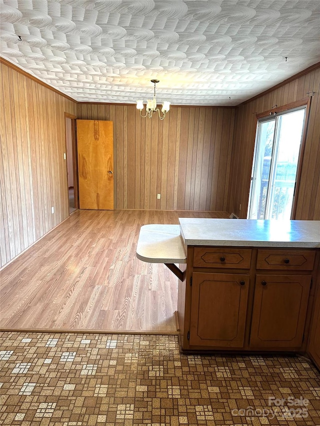 interior space with ornamental molding, wood walls, and a notable chandelier