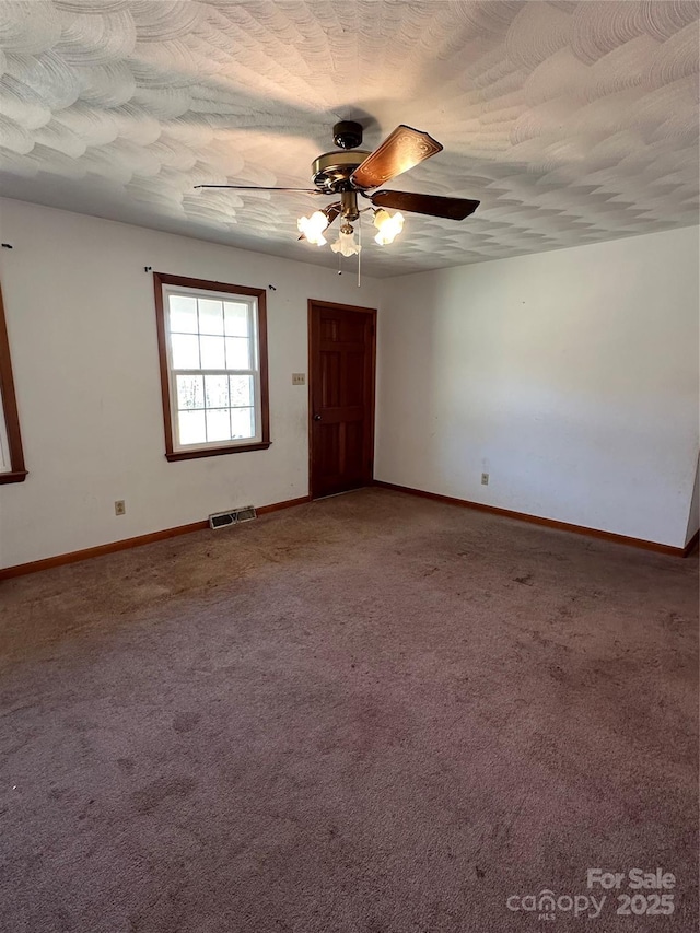 carpeted empty room featuring baseboards, visible vents, ceiling fan, and a textured ceiling