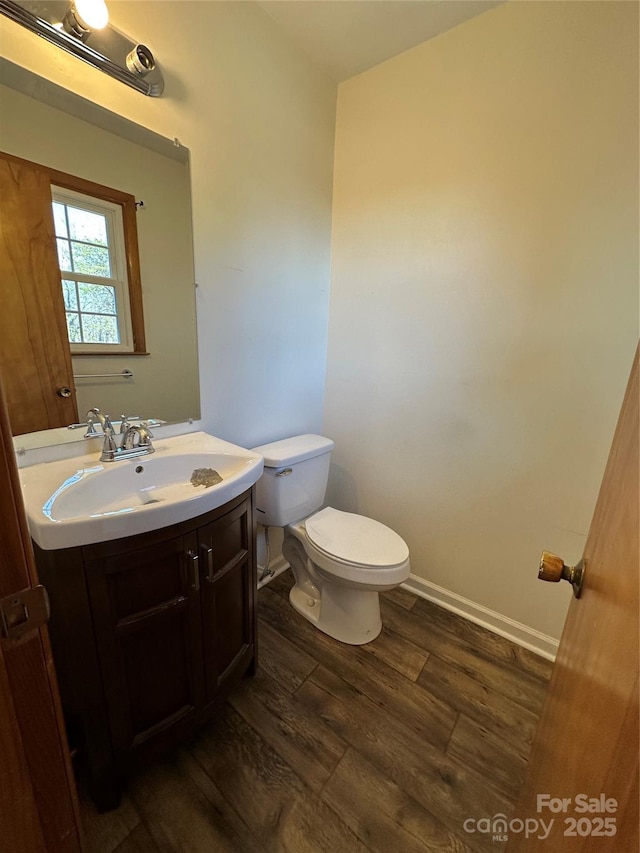 bathroom featuring toilet, wood finished floors, vanity, and baseboards