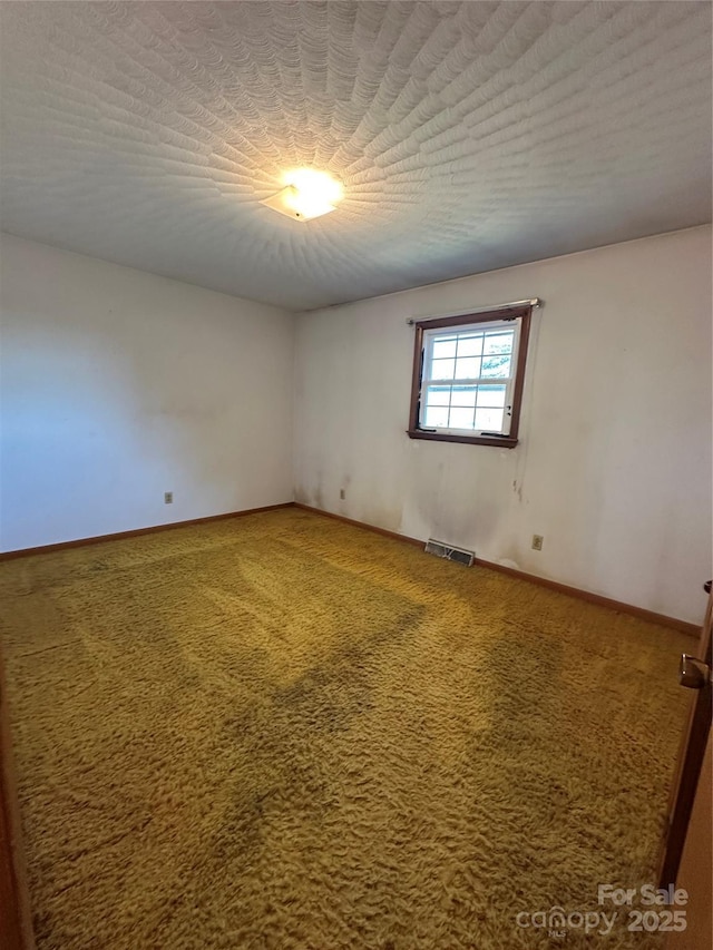 carpeted empty room with visible vents, a textured ceiling, and baseboards