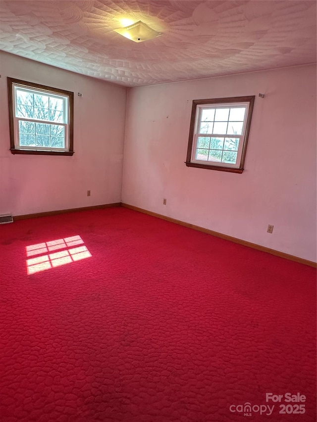 spare room featuring a wealth of natural light, carpet flooring, visible vents, and baseboards