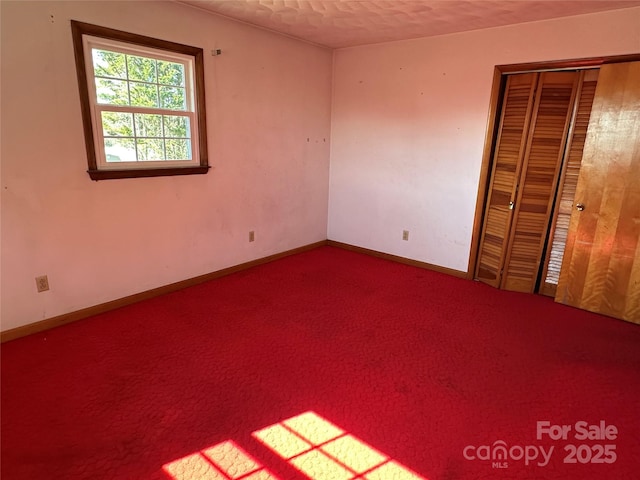 unfurnished bedroom with carpet, a closet, and baseboards