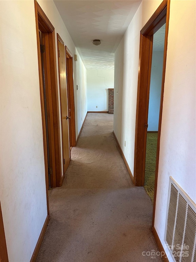 corridor with visible vents, light carpet, and baseboards