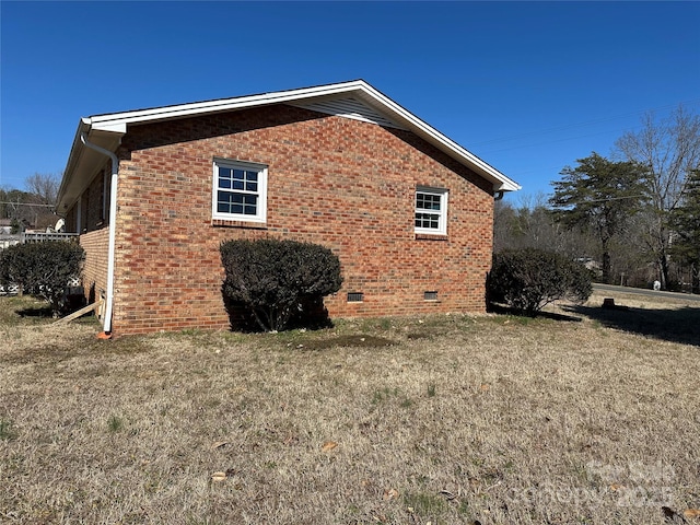 view of side of property featuring crawl space, a yard, and brick siding