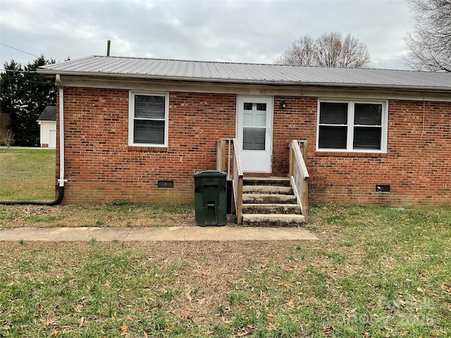 view of front facade featuring crawl space, a front yard, metal roof, and brick siding