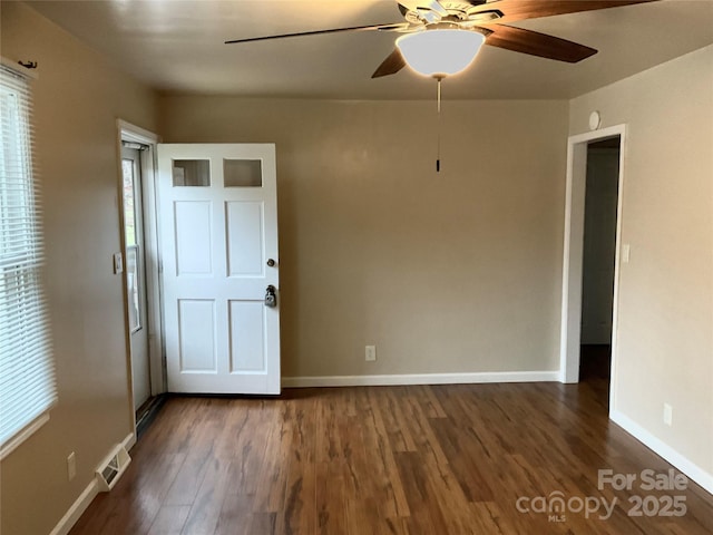 spare room with a ceiling fan, wood finished floors, visible vents, and baseboards