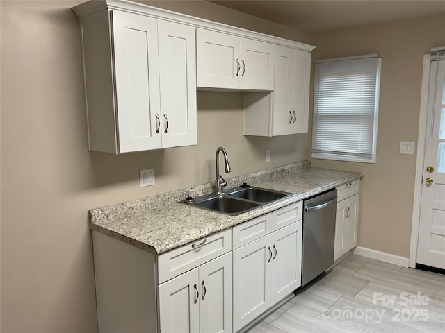 kitchen featuring light countertops, a sink, stainless steel dishwasher, and white cabinetry