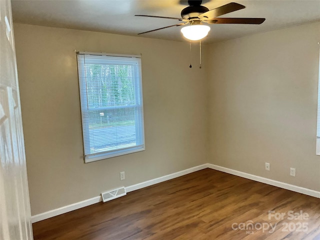 spare room with visible vents, dark wood finished floors, baseboards, and ceiling fan