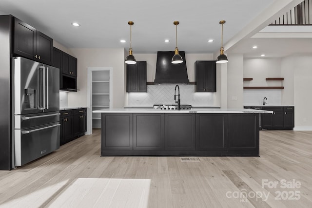 kitchen with stainless steel appliances, light countertops, custom exhaust hood, open shelves, and decorative light fixtures