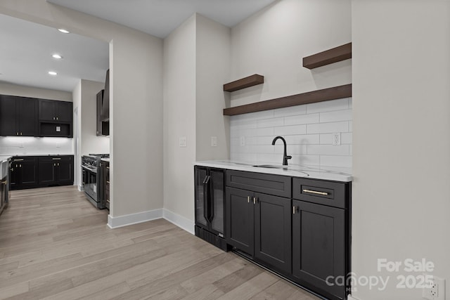 kitchen with open shelves, a sink, high end range, and light wood-style floors