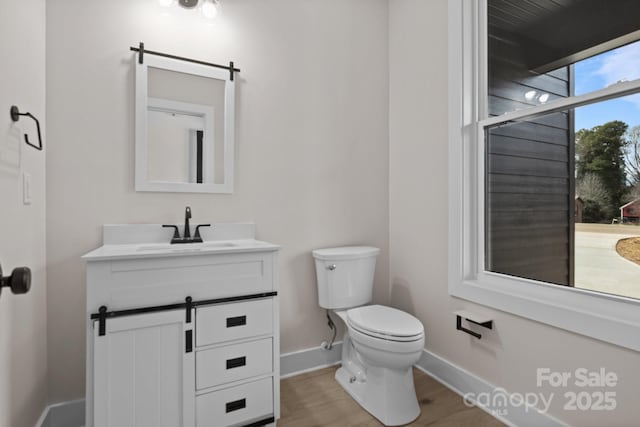 bathroom with toilet, baseboards, wood finished floors, and vanity