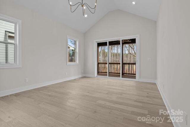 spare room with light wood finished floors, visible vents, baseboards, lofted ceiling, and a chandelier