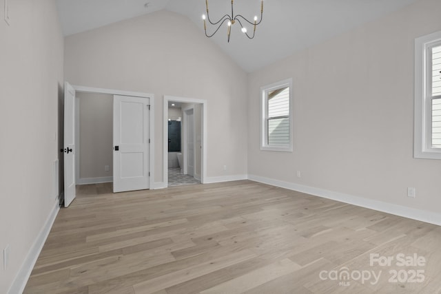 interior space with a chandelier, high vaulted ceiling, light wood-type flooring, and baseboards