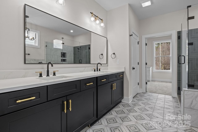 full bath with double vanity, a stall shower, a sink, and baseboards