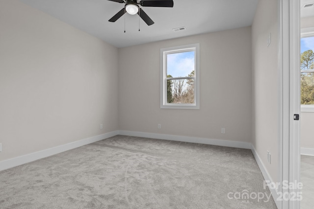 empty room featuring baseboards, visible vents, ceiling fan, and light colored carpet