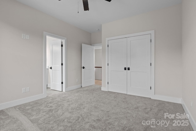 unfurnished bedroom with a ceiling fan, a closet, light colored carpet, and baseboards