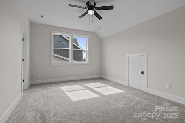 spare room featuring lofted ceiling, baseboards, light carpet, and visible vents