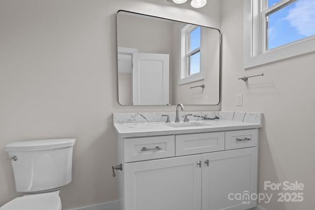 half bath with vanity, toilet, and baseboards