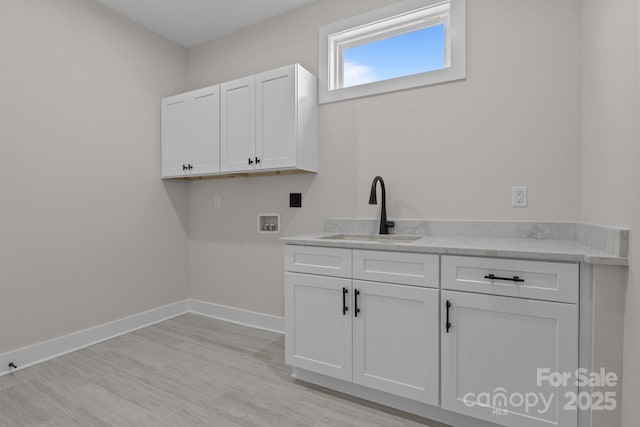 clothes washing area featuring washer hookup, cabinet space, a sink, and baseboards