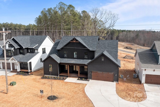 modern farmhouse style home with a shingled roof, concrete driveway, covered porch, board and batten siding, and central AC