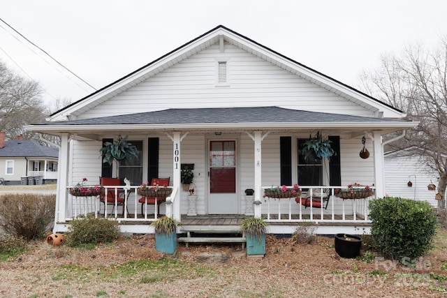 bungalow featuring a porch and roof with shingles