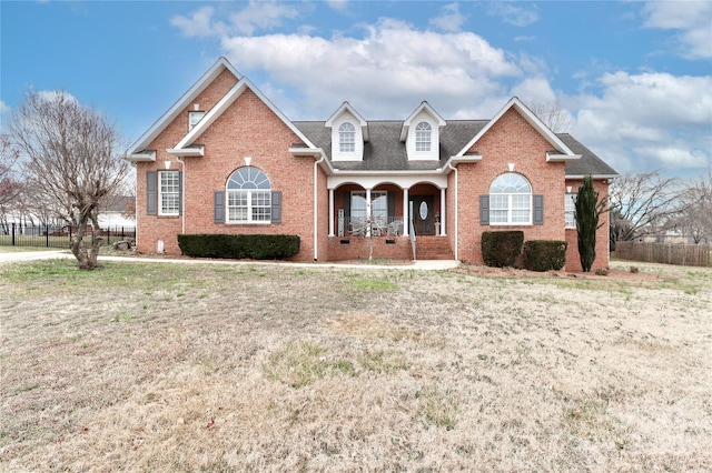 view of front facade featuring a front yard, covered porch, and brick siding