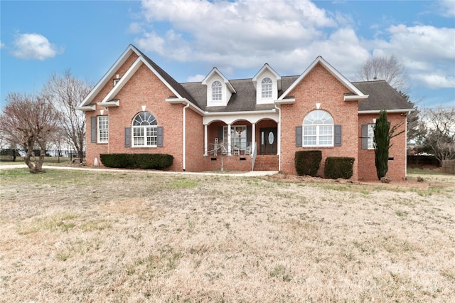 view of front of property featuring a porch, brick siding, and a front lawn