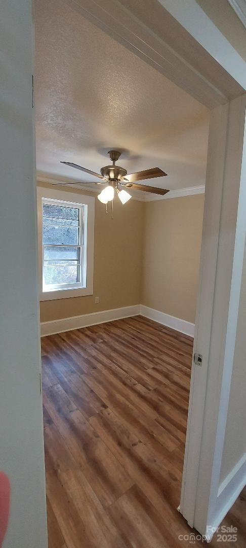 unfurnished room featuring dark wood-type flooring, a textured ceiling, baseboards, and a ceiling fan