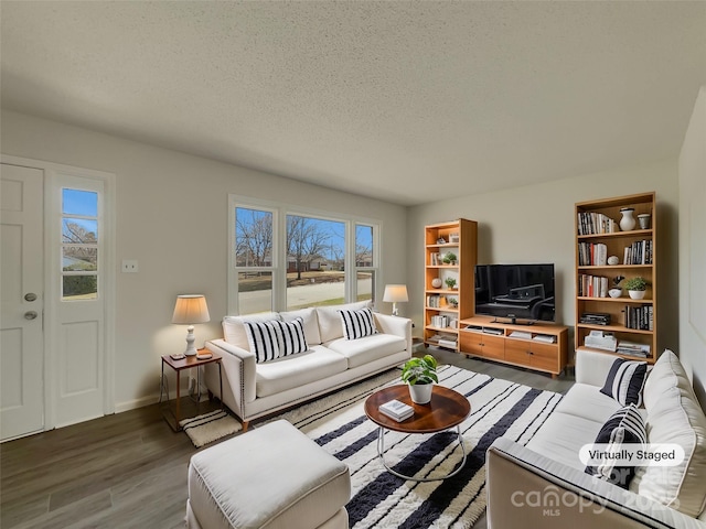 living room featuring a textured ceiling, baseboards, and wood finished floors