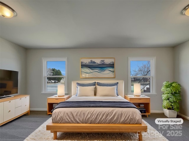 bedroom featuring baseboards, multiple windows, and dark carpet