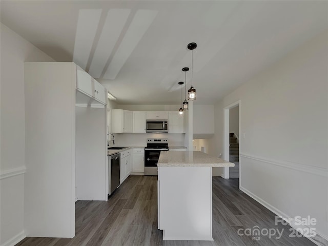 kitchen with appliances with stainless steel finishes, light countertops, a sink, and dark wood-style floors