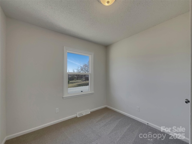 carpeted spare room featuring visible vents, a textured ceiling, and baseboards