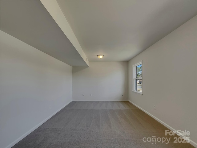 carpeted spare room featuring baseboards